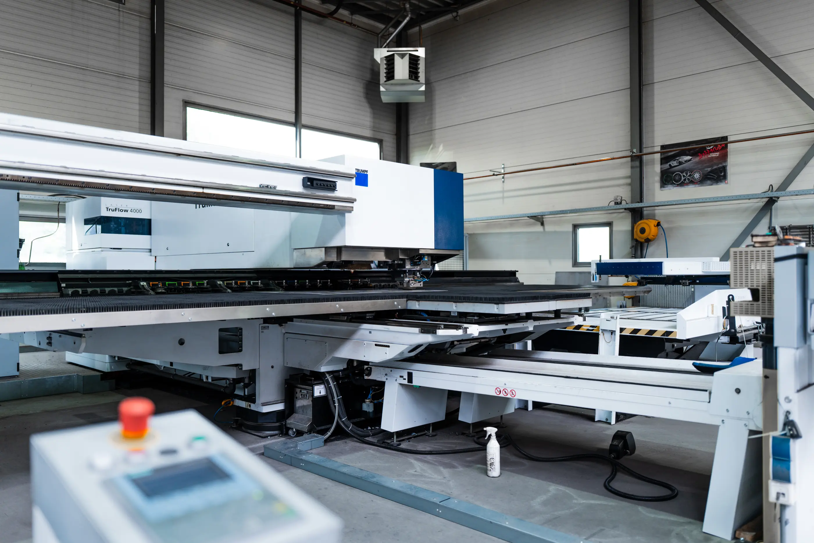 Witte Trumpf TruFlow 4000 plaatbewerkingsmachine in een industriële hal, met bedieningspaneel en noodstopknop op de voorgrond.